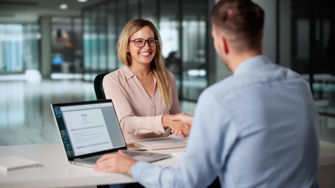 Uśmiechnięta klienta podająca dłoń w geście zawartej umowy.